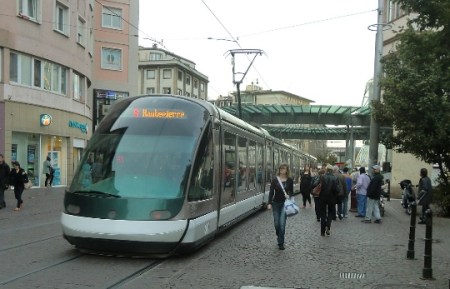 An A-Line tram approaches Homme de Fer (Iron Man) station as pedestrians stroll alongside the open track. Photo: Franz Roski.