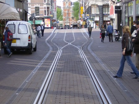 Focus on interlaced track construction in the Leidsestraat. Notice how the two tracks Notice how the two tracks virtually merge to form what almost seems like a single track — but there are separate parallel rails for each direction, laid next to each other. Also, only one rail in each direction actually cross each other (this type of passive, stationary rail crossing is called a frog).