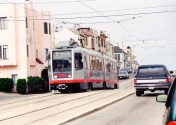 In this view of a train near 15th Avenue, the slightly raised center median reservation can be seen more clearly. Over the train, transverse spanwires holding OCS can be seen; other cross-wires are general utility cables. Photo (copyright) Eric Haas.